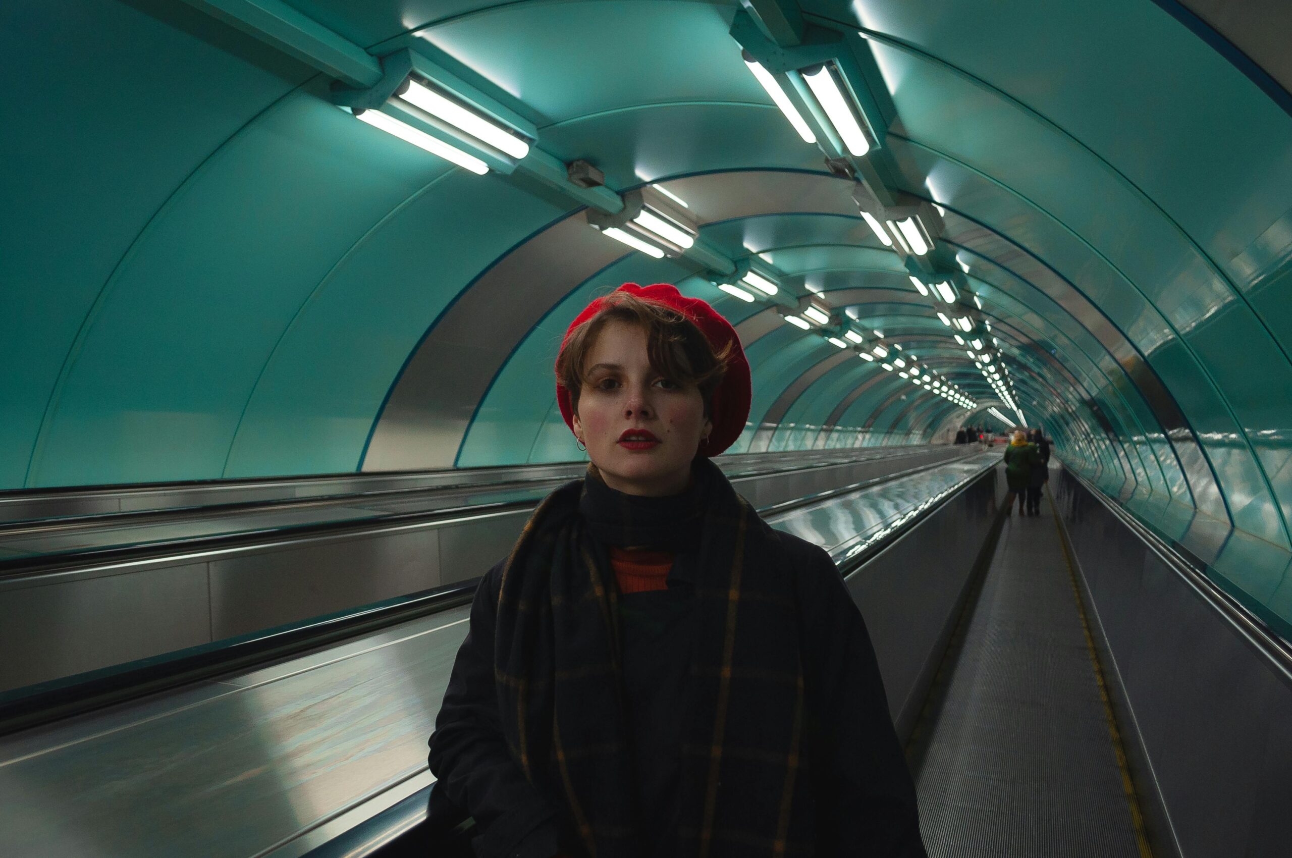 A woman in a red beret stands on a moving walkway in a metro tunnel, St. Petersburg.